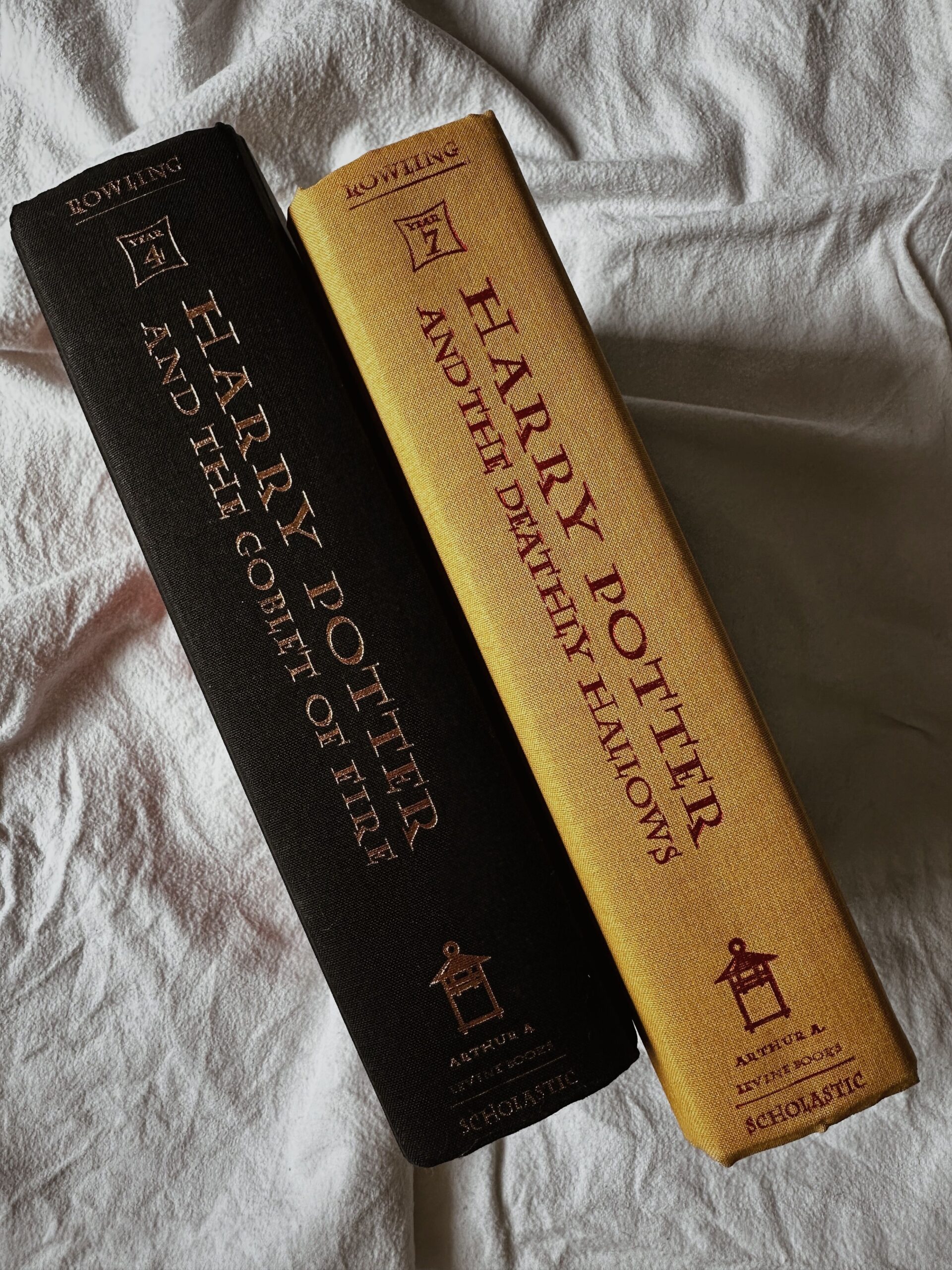 Close-up view of two Harry Potter books on a textured fabric surface.